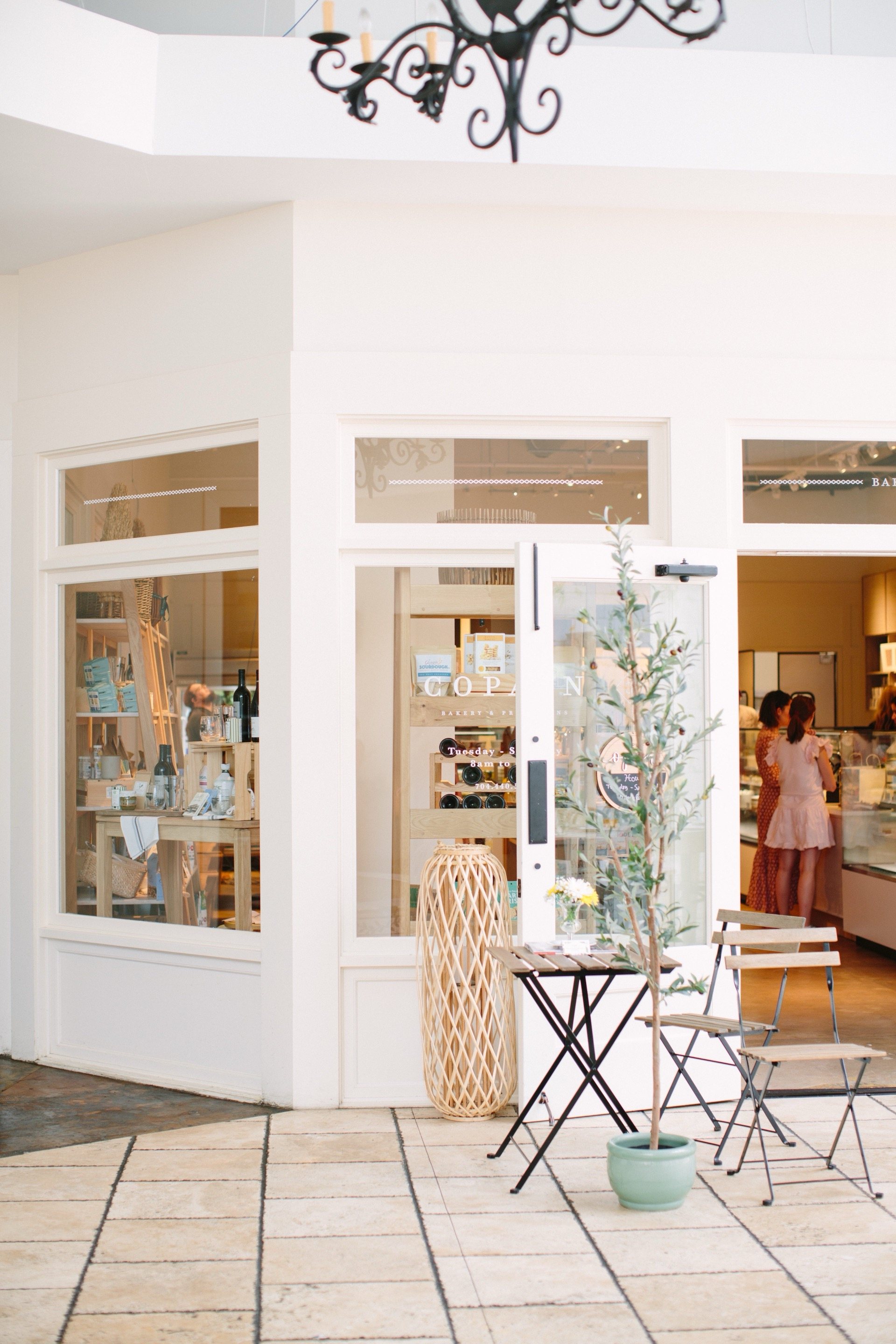 SouthPark — white French brasserie storefront with bistro furniture, olive tree and airy interior