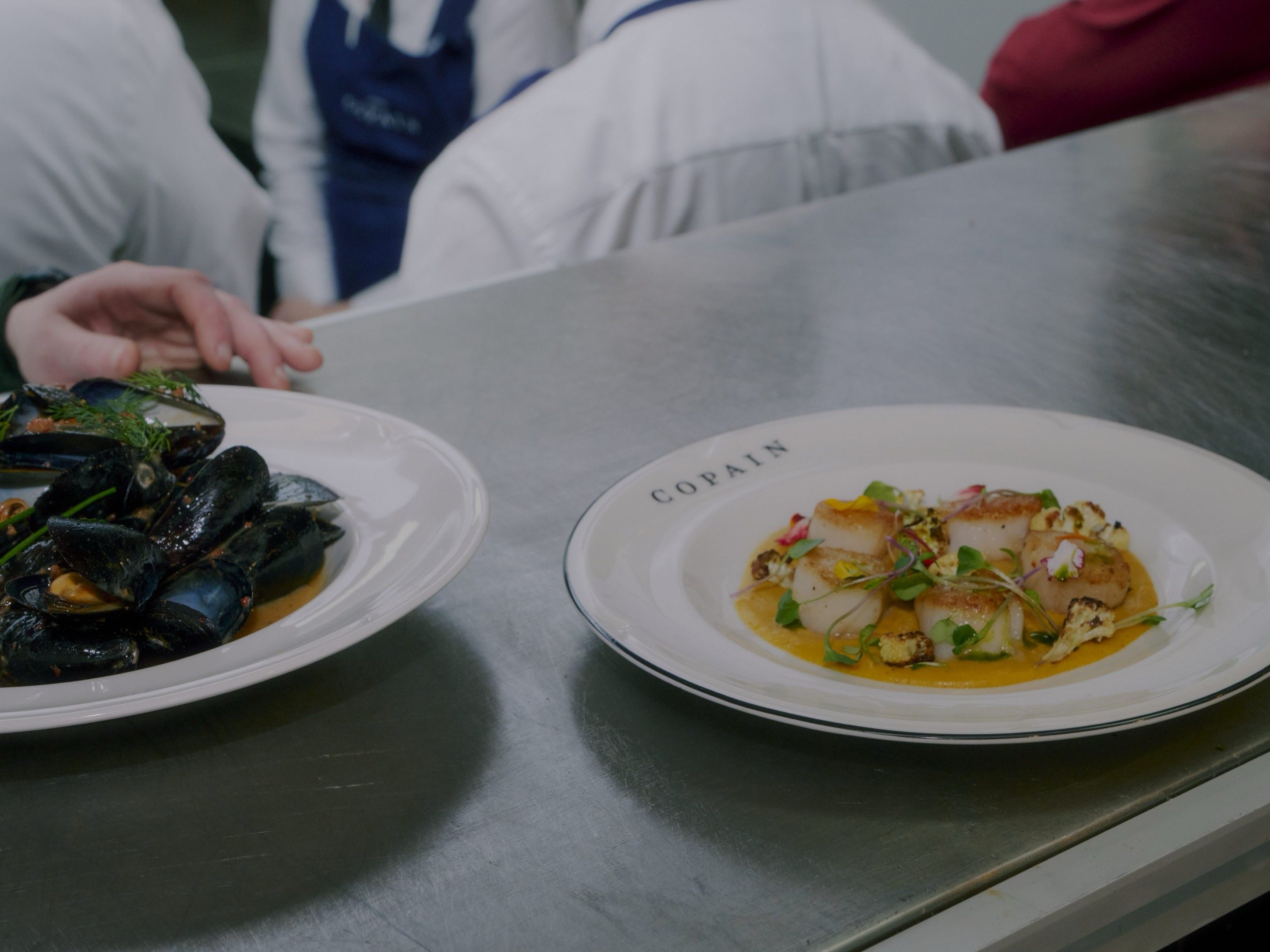 Moules marinière and seared scallops on the kitchen pass