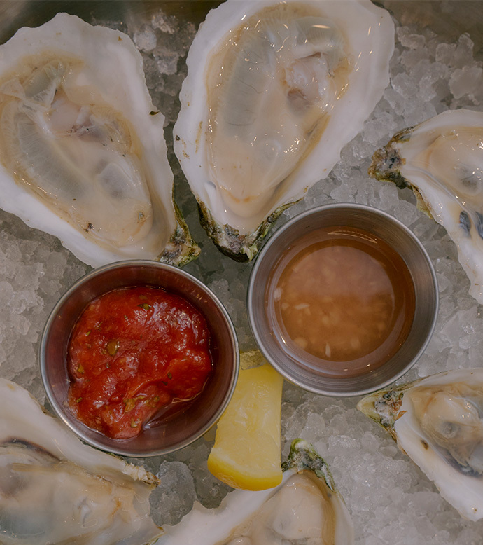 Oysters on ice with cocktail sauce, mignonette, and lemon