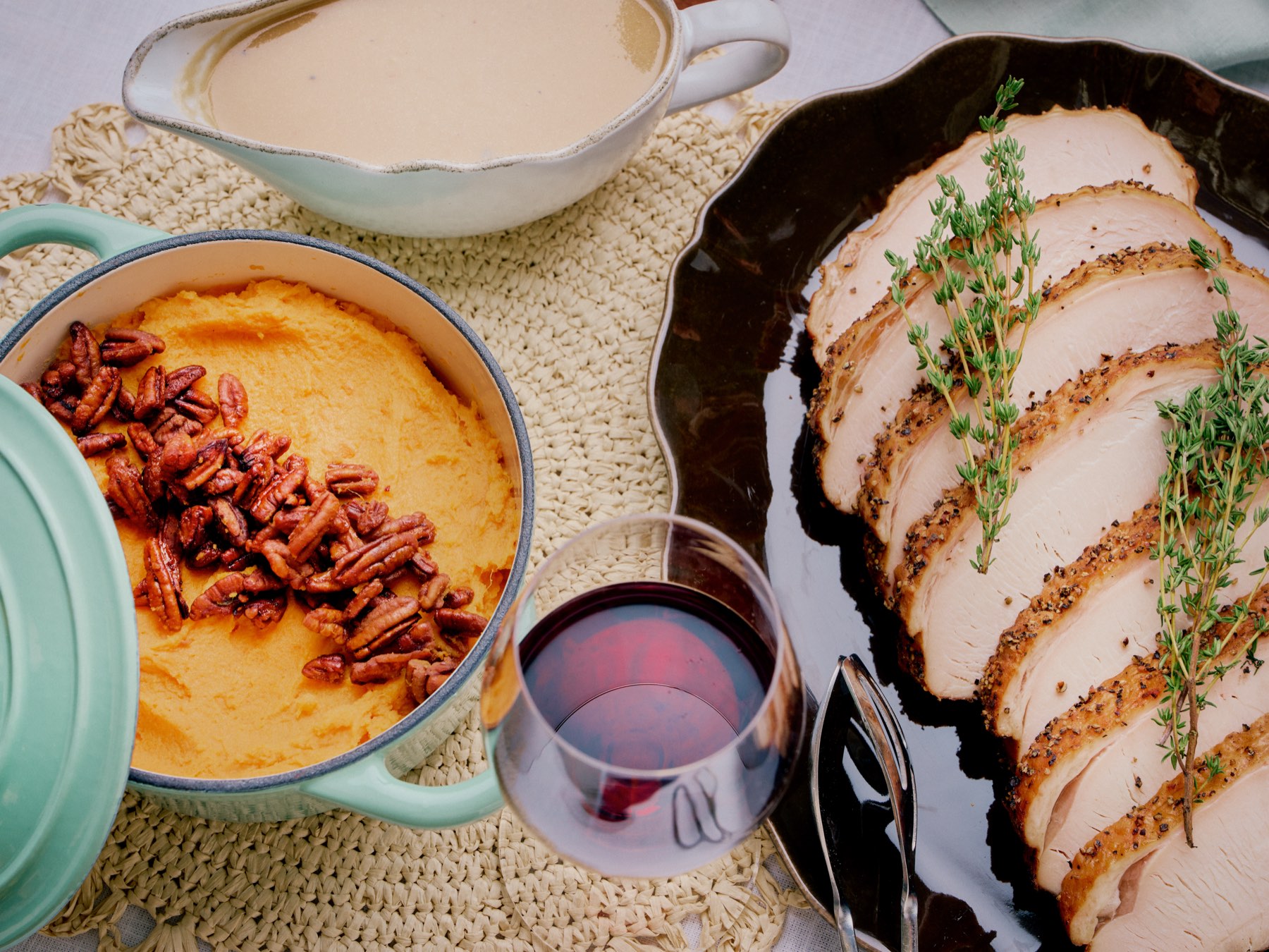 Smoked turkey breast with thyme, sweet potato casserole with pecan crumble, and gravy on a Thanksgiving table