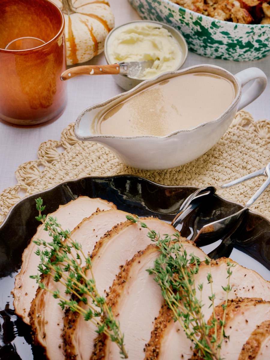 Sliced smoked turkey breast with thyme on a dark platter