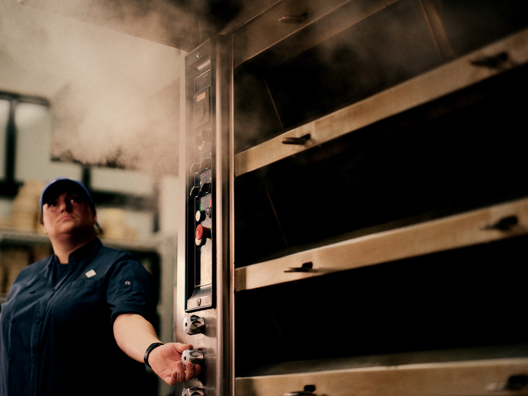 Copain baker opening the oven door as steam rises during the morning bake