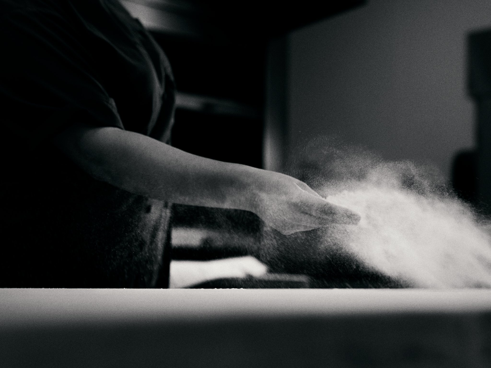 Copain baker dusting flour across the bench while making bread
